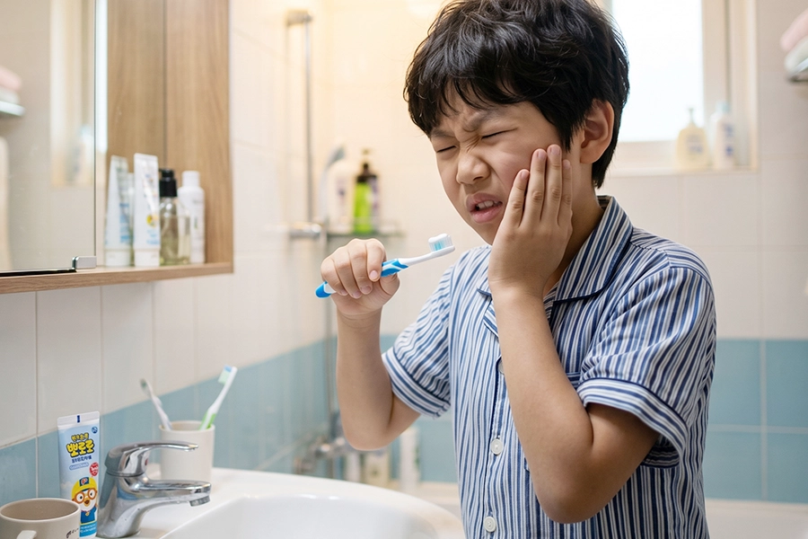 child-experiencing-tooth-pain-while-brushing 유치 충치 치료 안하면 양치질을 하다가 갑자기 심한 잇몸 통증과 치아 시림을 느끼는 어린이